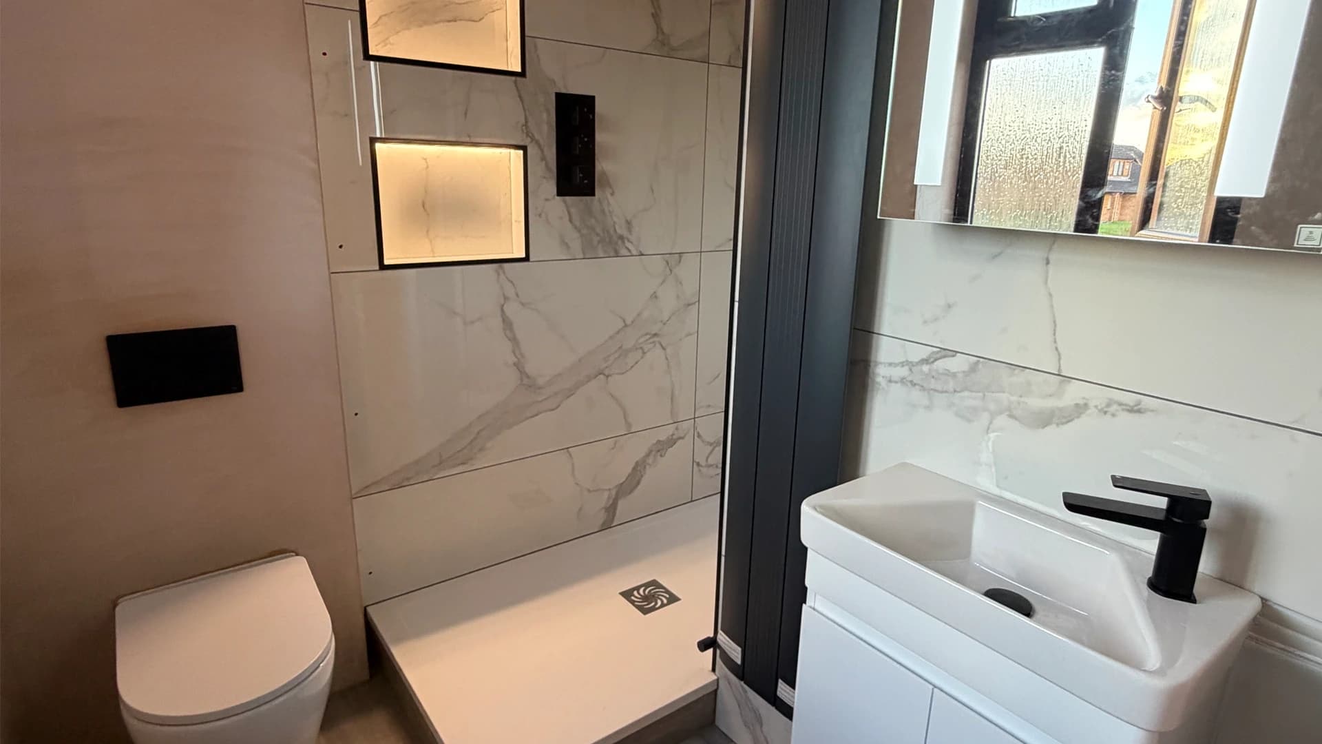 Modern bathroom installation in Bridgend featuring marble tiles and black fixtures